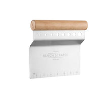 Load image into Gallery viewer, A metal bench scraper with a light wood handle, featuring a brushed silver metal blade with engraved text and ruler markings, and a wooden handle, shown on a plain white background. | Hadley Green Home