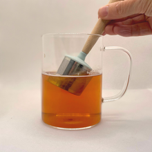 Load image into Gallery viewer, Clear glass mug with a wooden tea infuser in tea on a white background | Hadley Green Home