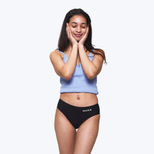 Load image into Gallery viewer, A girl posing in black WUKA period underwear and a light blue crop top against a solid white background. | Hadley Green Home