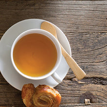 Load image into Gallery viewer, White cup of tea on a wooden surface with a pastry and a wooden spoon. | Little Twidlets 
