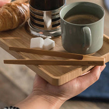 Load image into Gallery viewer, Hand holding a wooden tray with a mug of coffee, croissant, sugar cubes, and wooden tongs. | Little Twidlets
