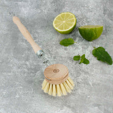 Load image into Gallery viewer, Dishwashing brush with wooden handle and bristles on a gray surface with lime halves and leaves.  | A Slice Of Green | Hadley Green Home
